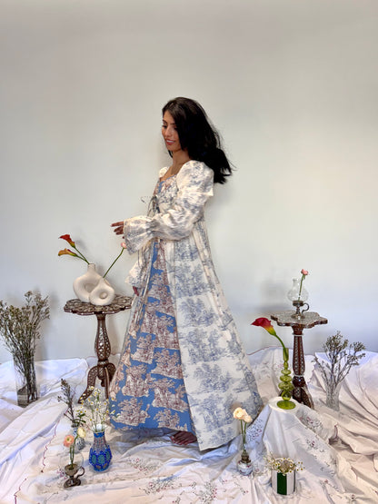 Woman in a floral dress standing in a room with decorative elements and flowers.